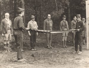 Scout Leaders Stand at Attention as Scouts Fold Flag